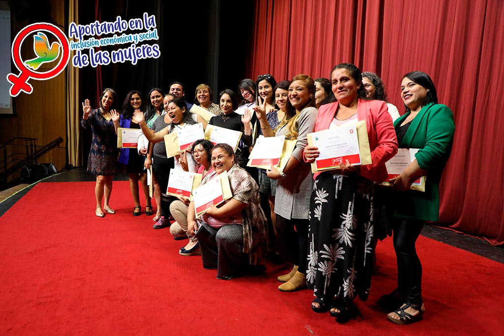 mujeres recibiendo diploma de capacitación de oficio en escenario.